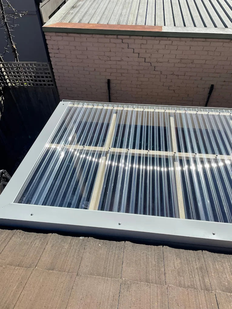 Solar panel on a roof with a brick wall and metal roof in the background