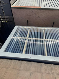 Solar panel on a roof with a brick wall and metal roof in the background