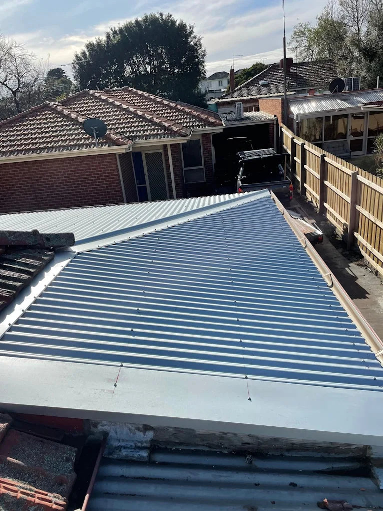 Metal roof with striped pattern, surrounded by residential buildings and trees.
