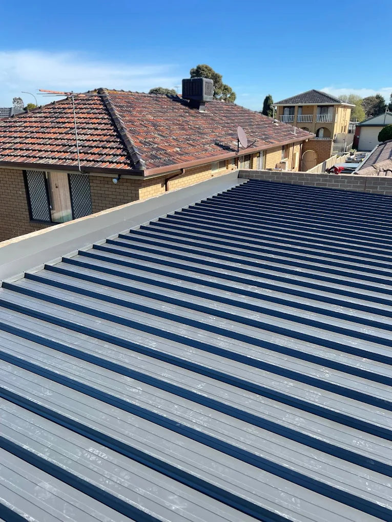 Roof with metal shingles under a clear blue sky - Bill Roofing 
