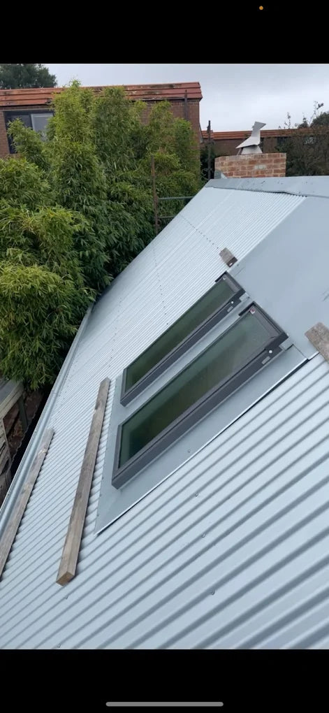 Skylight on a roof with trees and buildings in the background