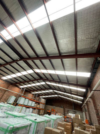Interior of a warehouse with stacked boxes and a high ceiling. - Bill Roofing 