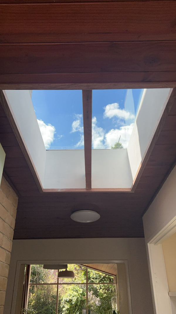 Skylight in a ceiling with a view of blue sky and clouds. - Bill Roofing 