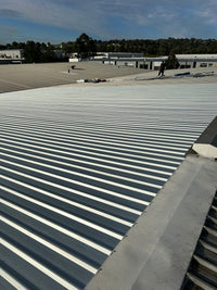 Roof with corrugated metal panels under a clear blue sky - Bill Roofing 