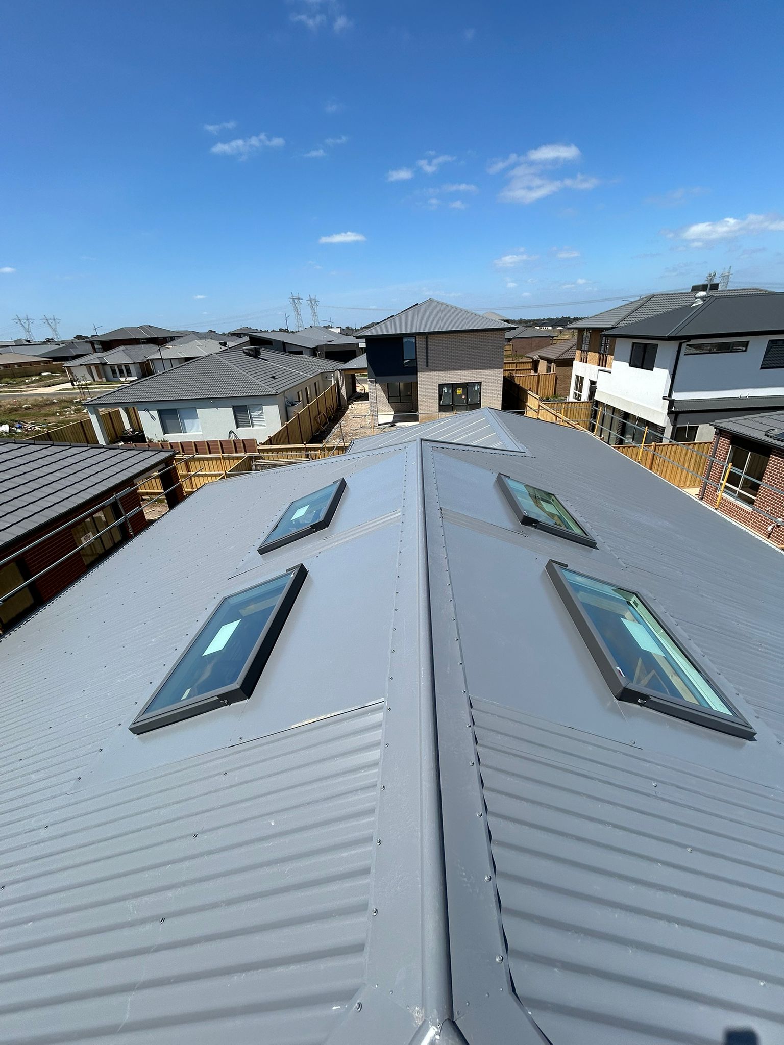 Roof with skylights and residential area in the background - Bill Roofing 