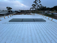 Roof with skylights and surrounding area with trees and buildings - Bill Roofing 