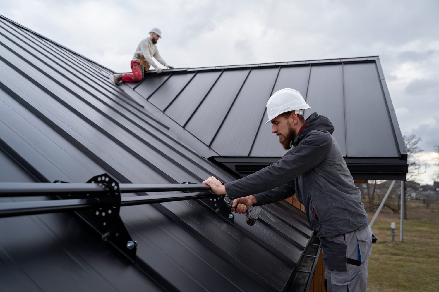 Two workers installing solar panels on a roof - Bill Roofing 