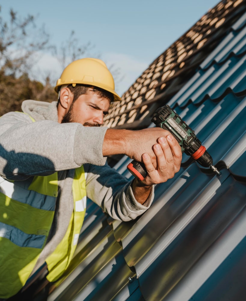 Person using a drill on a roof - Bill Roofing 