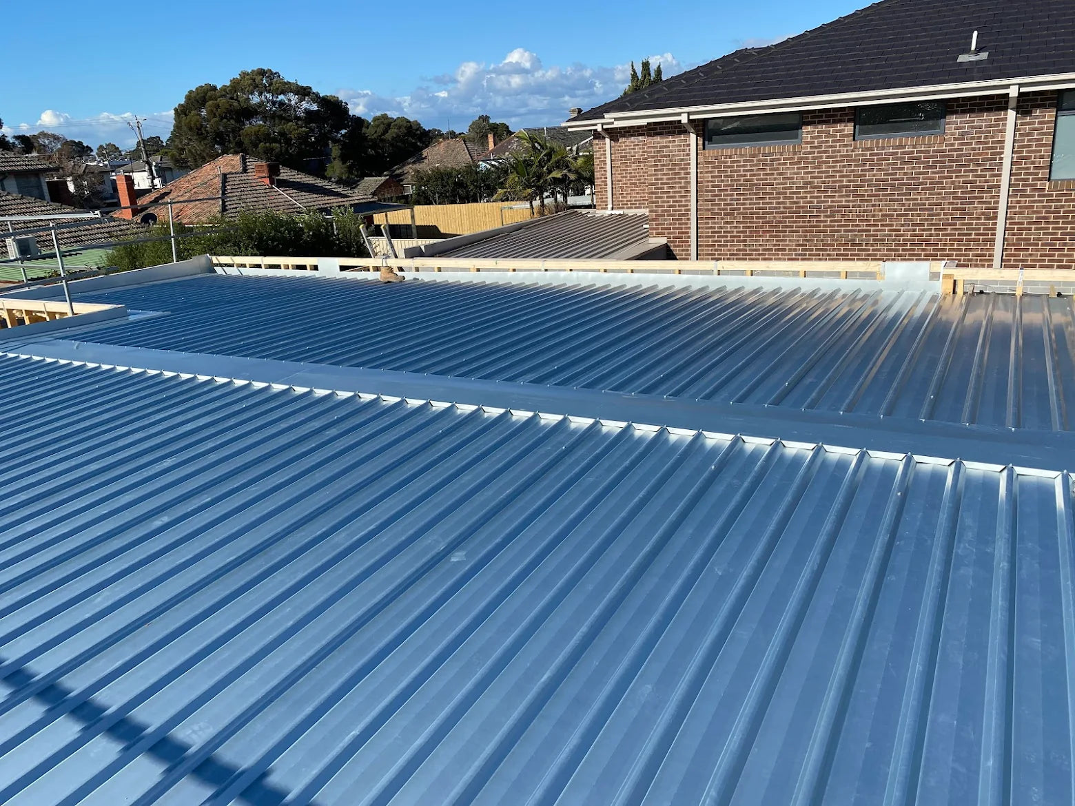 Newly installed metal roof on a residential house with clear blue sky. - Bill Roofing 
